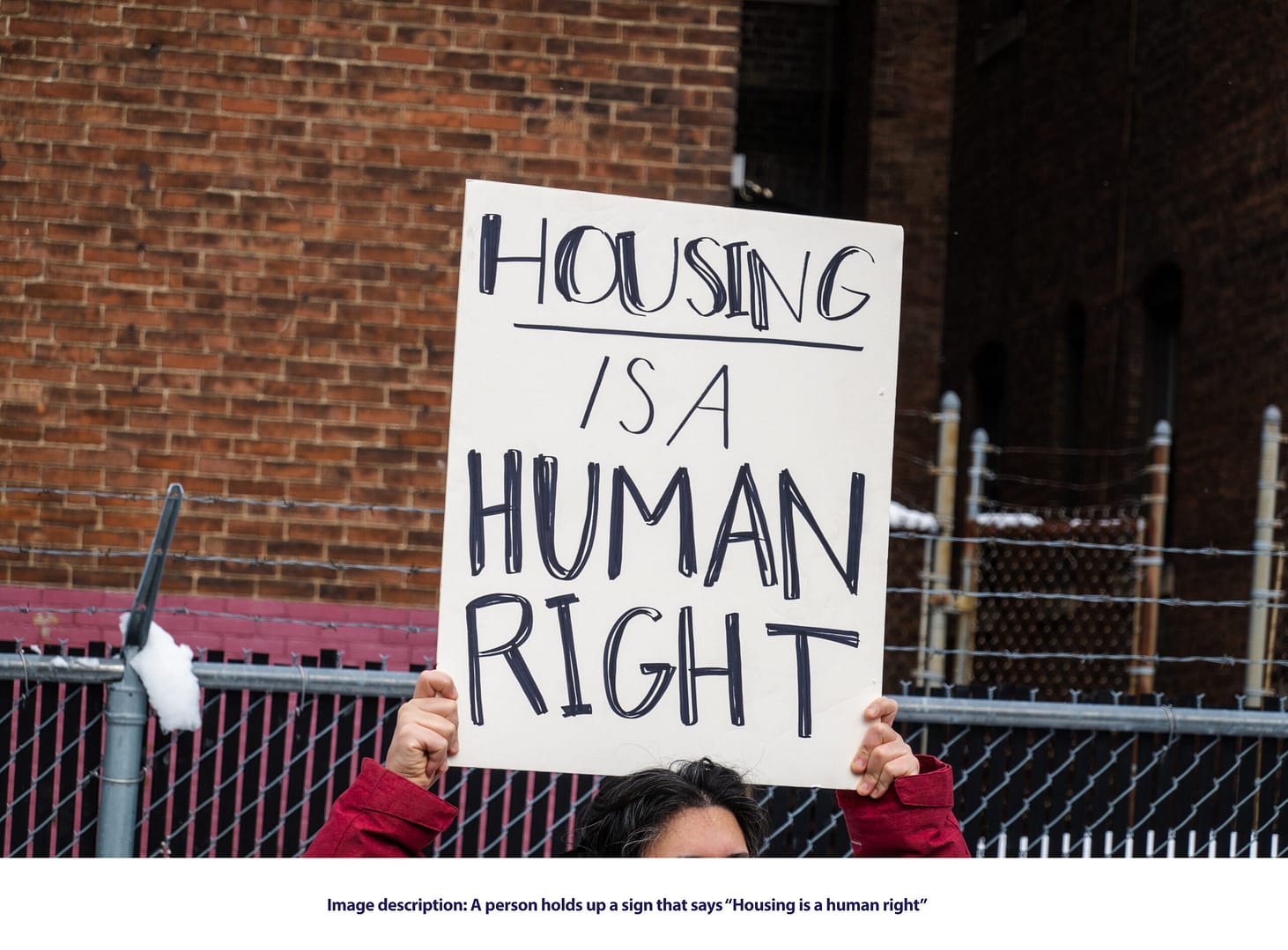 A person holds up a sign that says "Housing is a human right."