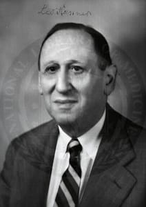 Dr. Leo Kanner, seen in a black and white photo from the chest up. He is wearing a suit with a striped tie, and has short dark hair.