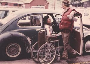 woman getting out of her old fashioned beetle car into her wheelchair