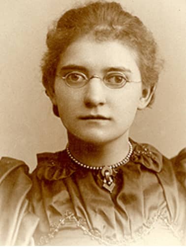 Agatha Teigel hanson in a sepia-toned photo, taken from the chest up. She is wearing a dark blouse with a frilled collar, and wire-rimmed glasses.