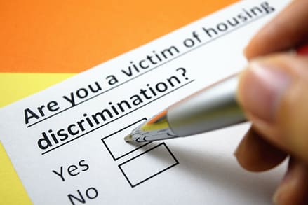 A person is answering question on a form about housing discrimination.